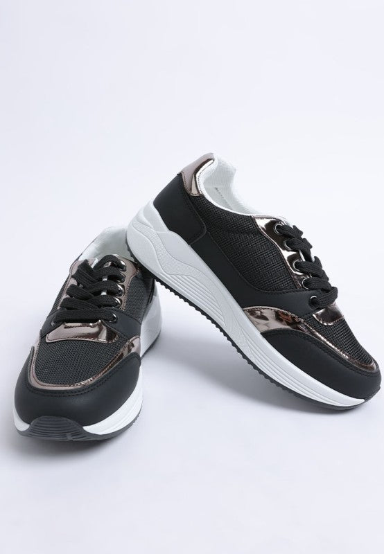 Black and white sneakers with metallic accents on a light gray background