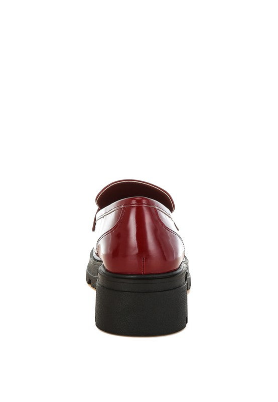 Red leather shoe with a thick black sole on a white background