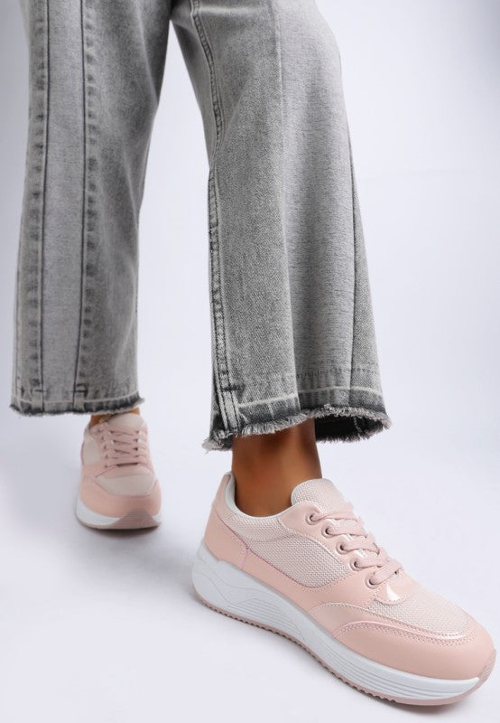 Pink sneakers worn with gray jeans on a light gray background