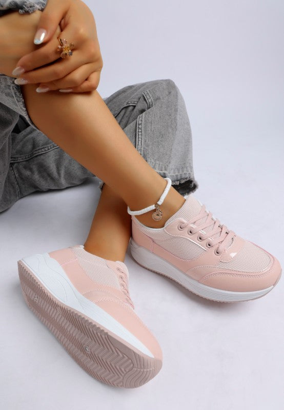 Pink sneakers worn with gray jeans on a light background