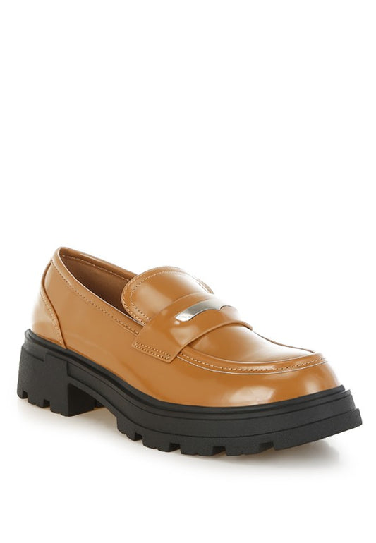 Tan loafer shoe with a thick black sole on a white background